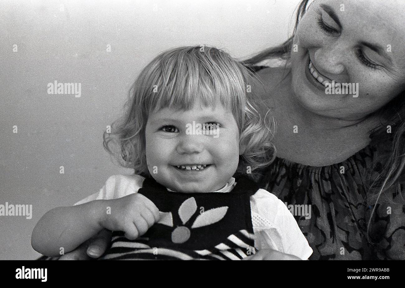 anni '1970, ragazza sorridente con madre. Foto Stock