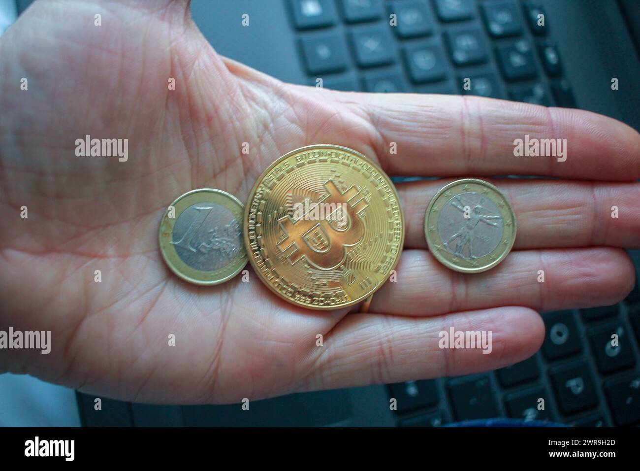 un bitcoin e due euro nel palmo della mia mano. Il valore della cripto Foto Stock