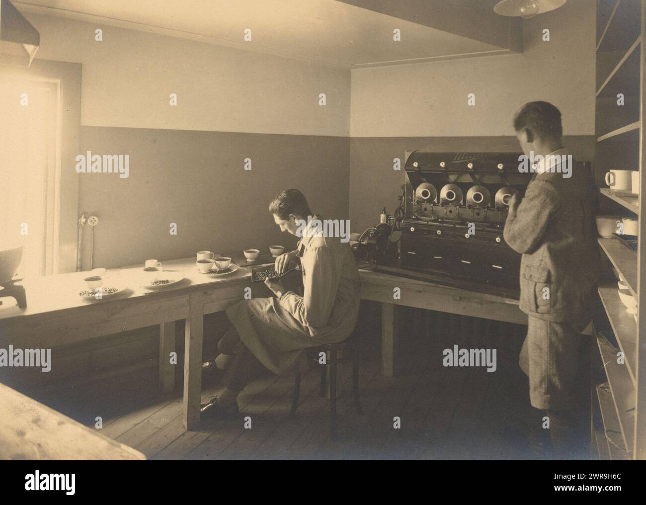 Due uomini controllano la qualità del caffè in un magazzino, probabilmente N.V. Het Nederlandsche Veem, questa foto fa parte di un album., anonimo, Amsterdam, 1900 - 1930, cartone, stampa in argento gelatina, altezza 165 mm x larghezza 222 mm, fotografia Foto Stock