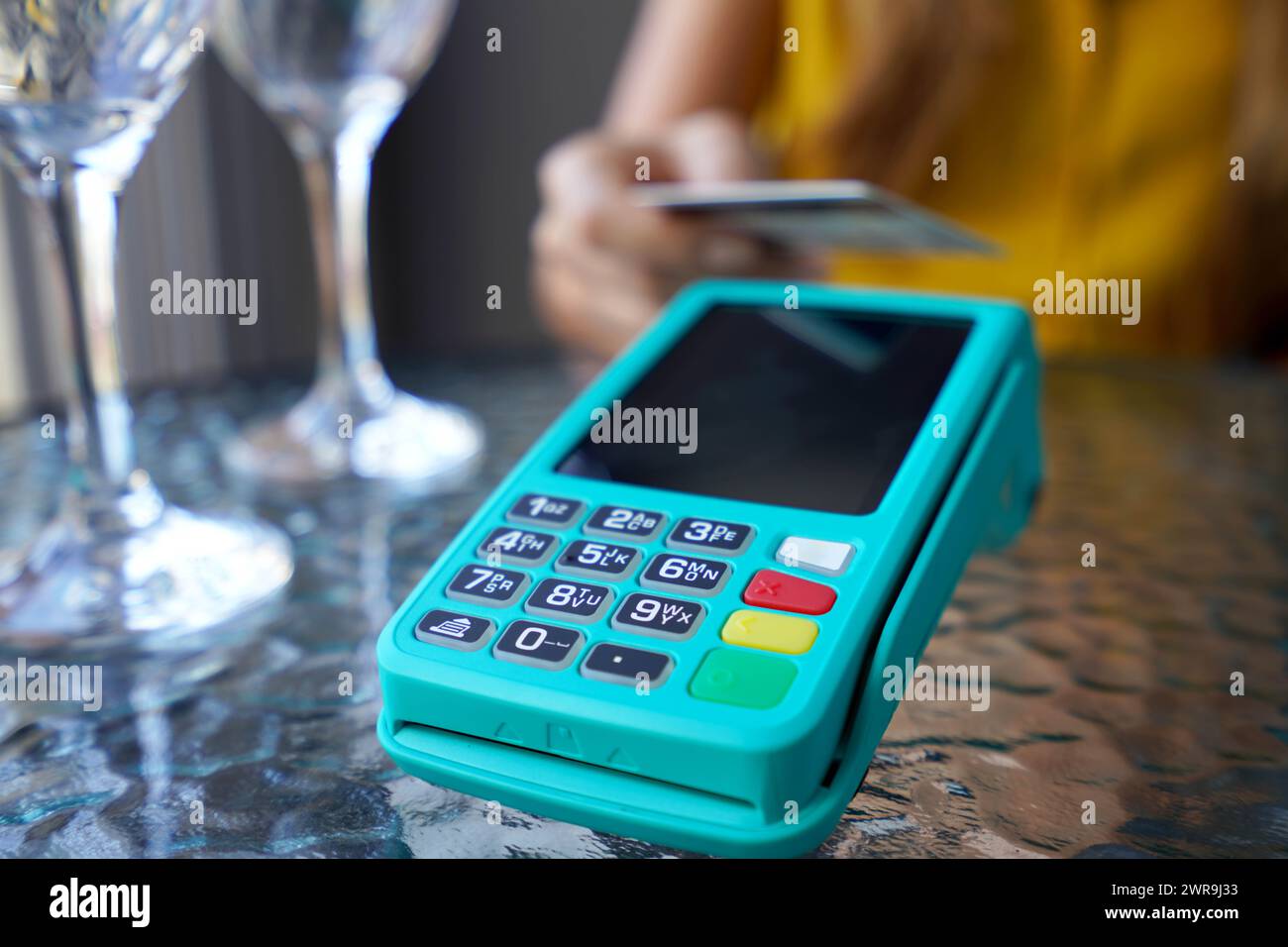 Primo piano estremo di clienti irriconoscibili che utilizzano la carta di credito per il pagamento online. Pagamento contactless NFC con carta di credito e terminale POS al bar. Foto Stock