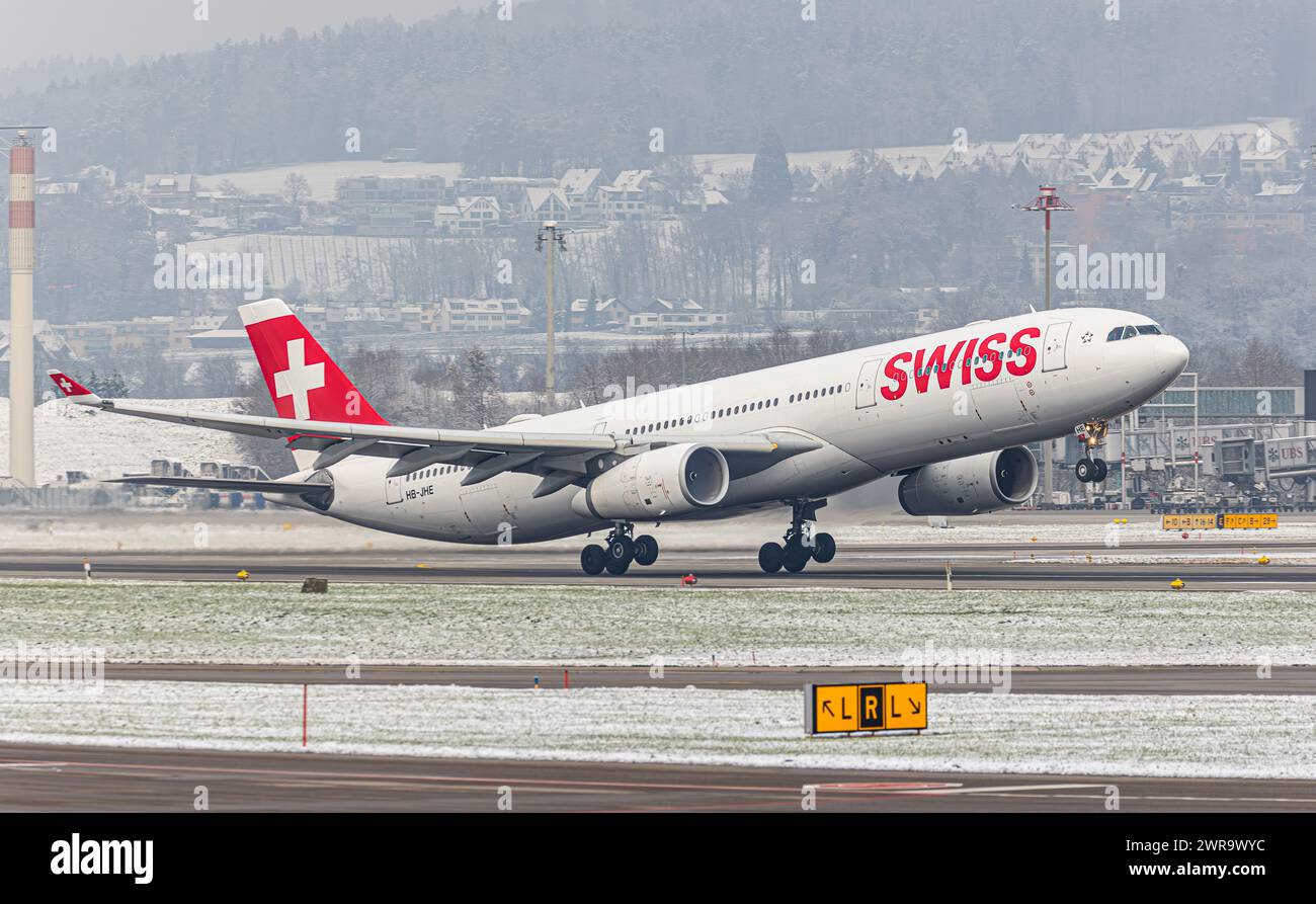 Ein Airbus A330-343X von Swiss International Airlines startet von Startbahn 16 des sich in winterlicher Landschaft befindlichen Flughafen Zürich. Reg Foto Stock