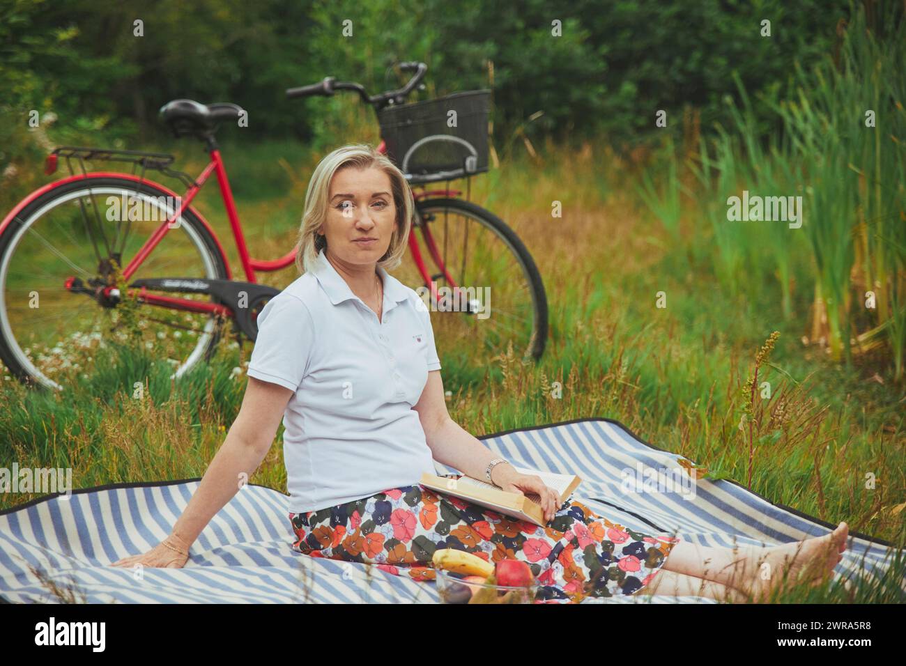 Aalborg, Danimarca, 23 luglio 2022: Donna matura che legge un libro sul fiume Foto Stock