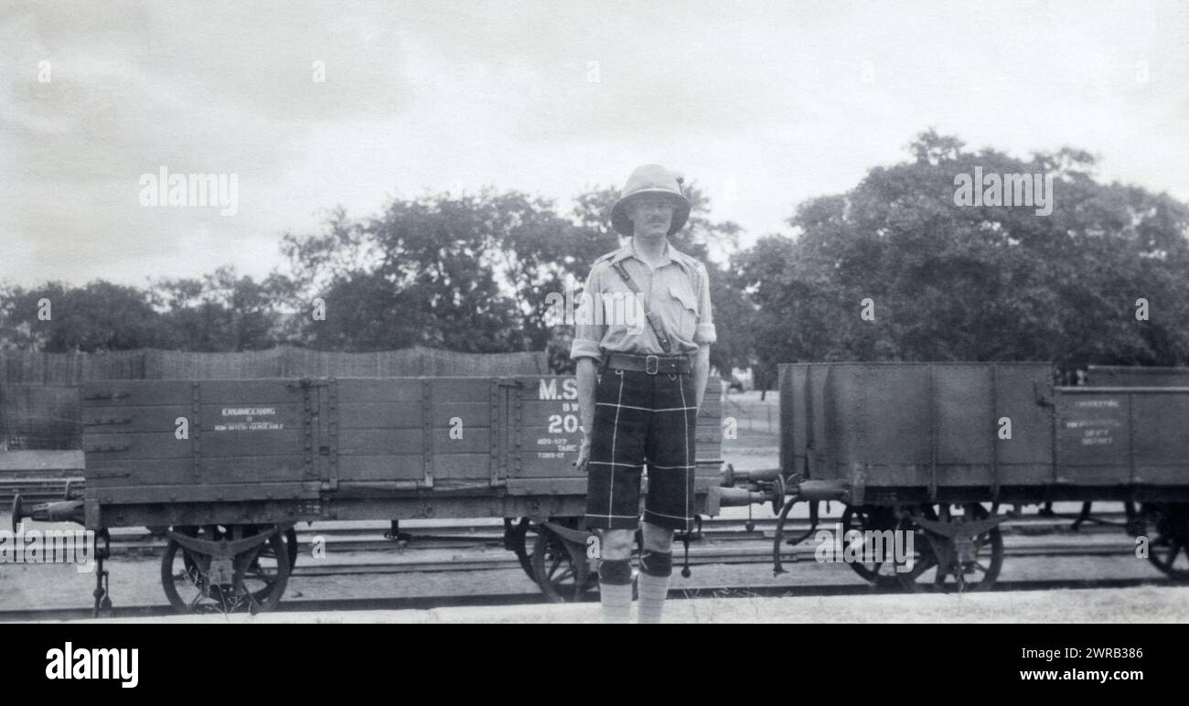 Un maggiore nel 2nd Battalion Highland Light Infantry di fronte a Madras e Southern Mahratta Railway Trucks in British India, 1925 circa. Foto Stock