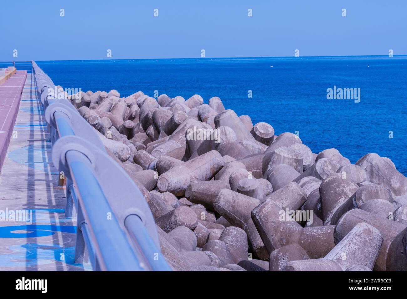 I tetrapodi di cemento sono un passaggio costiero sotto cieli limpidi, con un oceano blu vivace sullo sfondo, in Corea del Sud Foto Stock