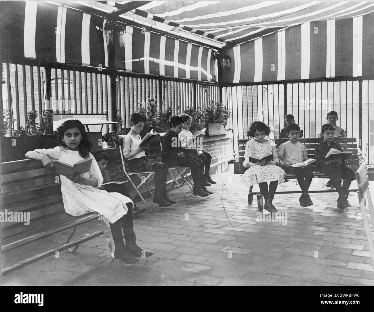 Bambini che leggono nel giardino sul tetto di Rivington St Library, New York City(?), CA. 1919, bambini, 1910-1930, stampe fotografiche, 1910-1930., stampe fotografiche, 1910-1930, 1 stampa fotografica Foto Stock