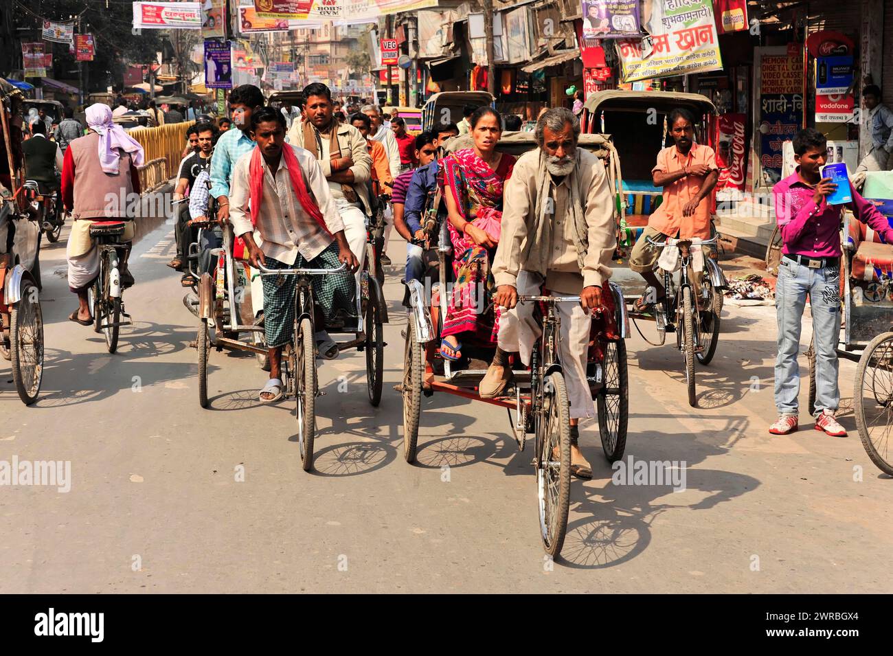 Vivace scena di strada con molti risciò ciclabili e passanti, Varanasi, Uttar Pradesh, India Foto Stock