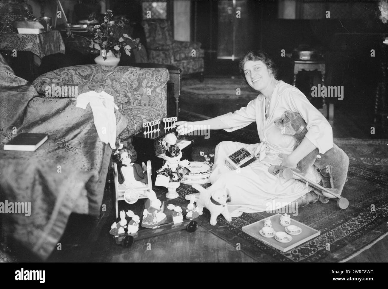 Gluck, la fotografia mostra la cantante d'opera rumena-americana Alma Gluck (1884-1938) seduta sul pavimento con giocattoli per Natale, tra cui un pianoforte giocattolo Schoenhut, set di parole "Tinkerblox", scatola di cioccolato Maillard, bambole, set da tè, gatto imbottito e orso imbottito su ruote (probabilmente prodotto da Steiff), tra ca. 1915 e ca. 1920, Glass negative, 1 negativo: Glass Foto Stock