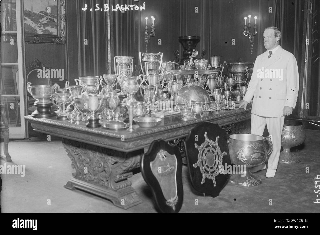 J.S. Blackton, la fotografia mostra il regista J. Stuart Blackton (1875-1941) in piedi accanto a un tavolo con vasi d'argento e altri oggetti. 1915 e ca. 1920, Glass negative, 1 negativo: Glass Foto Stock