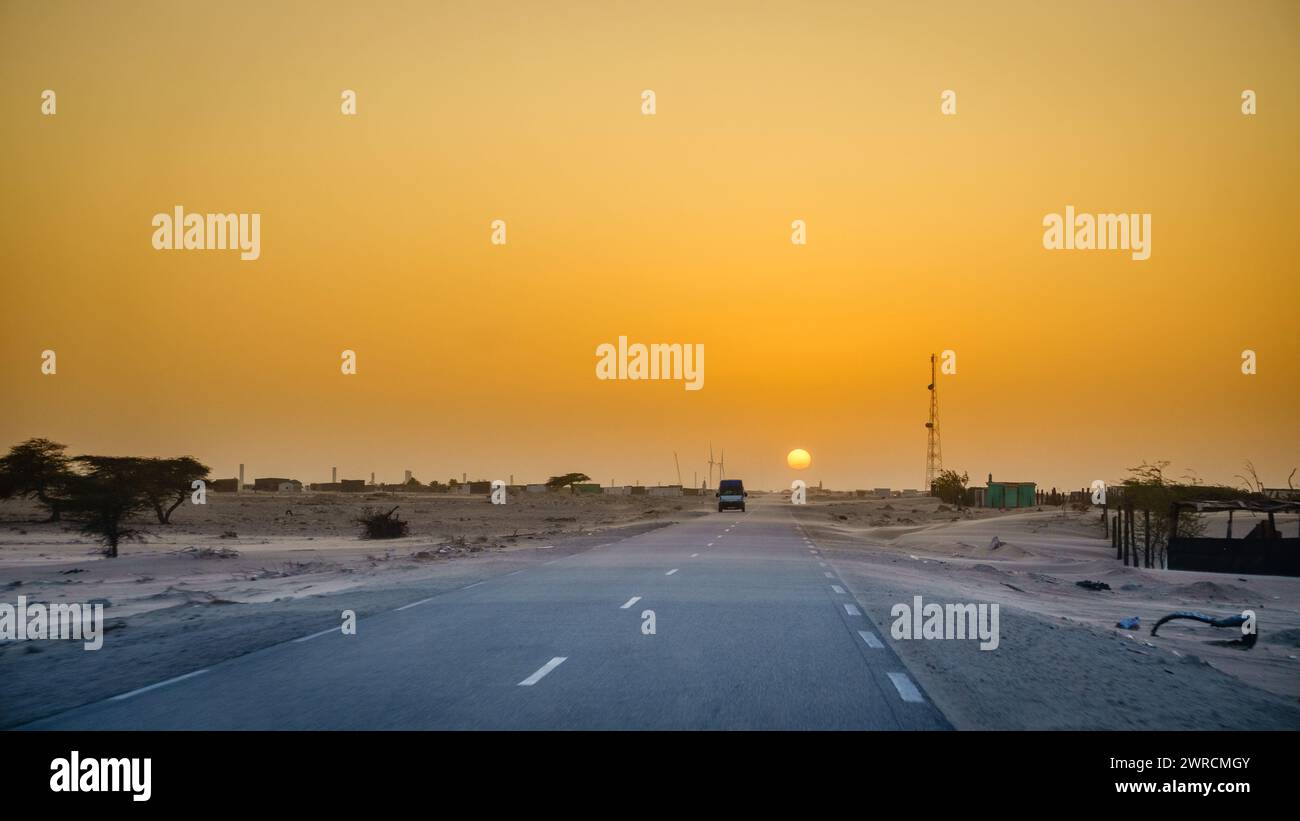 Guida attraverso un villaggio nel deserto in Mauritania al tramonto Foto Stock