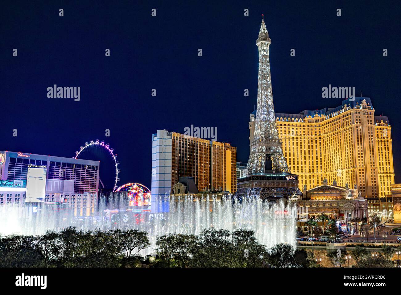 Las Vegas Boulevard strip fontane Bellagio / casinò di Parigi di notte 2024 - luci della città cartelli colorati e attrazioni turistiche sfera e High Roller Foto Stock