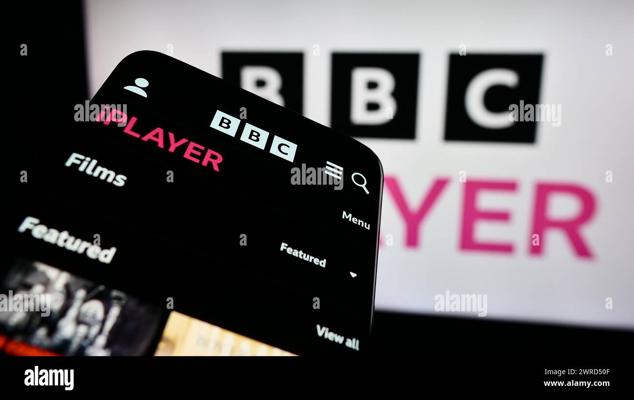 Smartphone con sito Web del servizio video on demand britannico BBC iPlayer davanti al logo aziendale. Mettere a fuoco in alto a sinistra sul display del telefono. Foto Stock