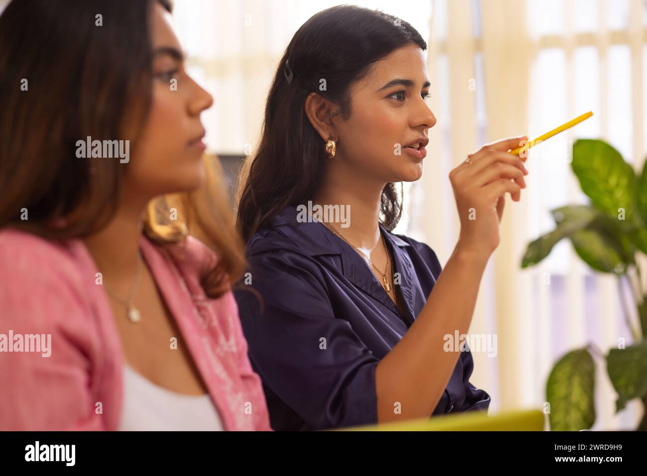 Giovane donna che condivide la sua esperienza durante una riunione d'affari in ufficio Foto Stock