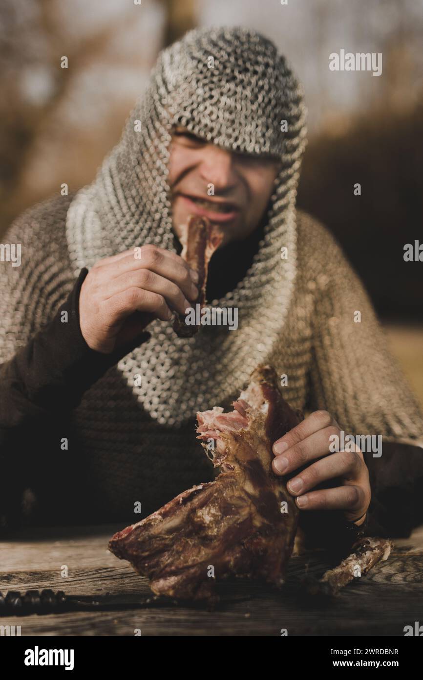 Fanteria medievale uomo armato seduto accanto al tavolo di legno Foto Stock