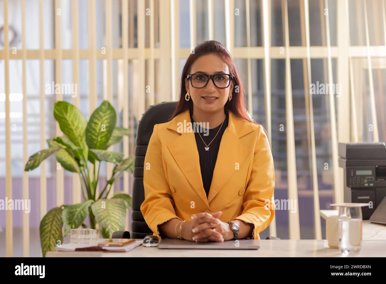 Ritratto di una bella donna d'affari felice seduta nel suo ufficio e che guarda la fotocamera Foto Stock