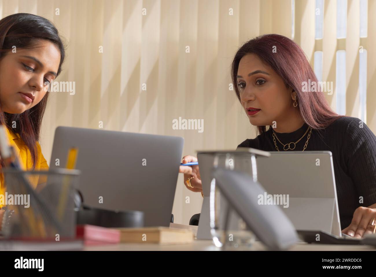 Due donne d'affari che discutono di un progetto alla postazione di lavoro dell'ufficio Foto Stock