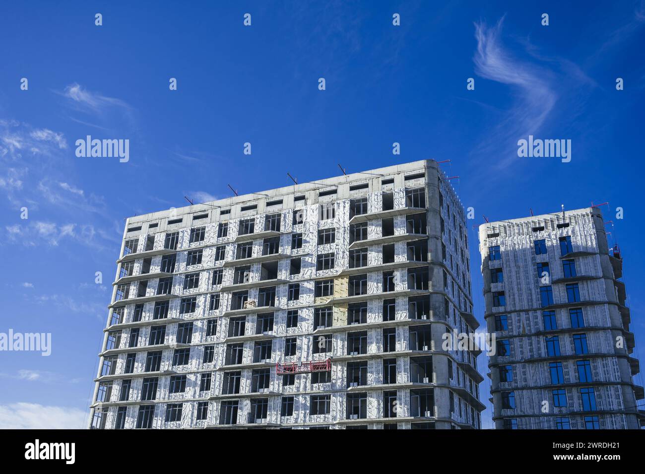 SHYMKENT, KAZAKHSAN - 3 GENNAIO 2024: Edificio residenziale in costruzione con pannelli di isolamento termico installati sulla facciata su sfondo blu Foto Stock