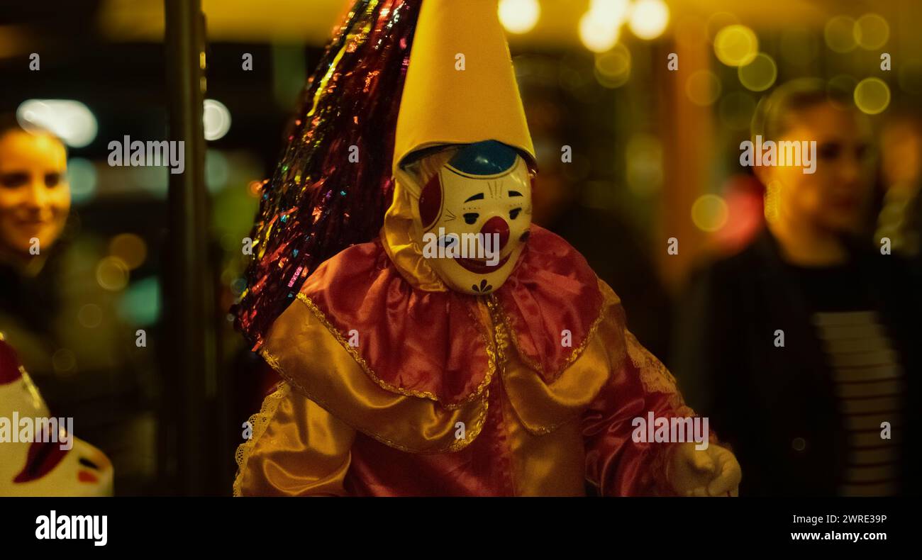 Immagine di due clown, uno che indossa una grande maschera facciale e un vestito rosso, in piedi insieme Foto Stock