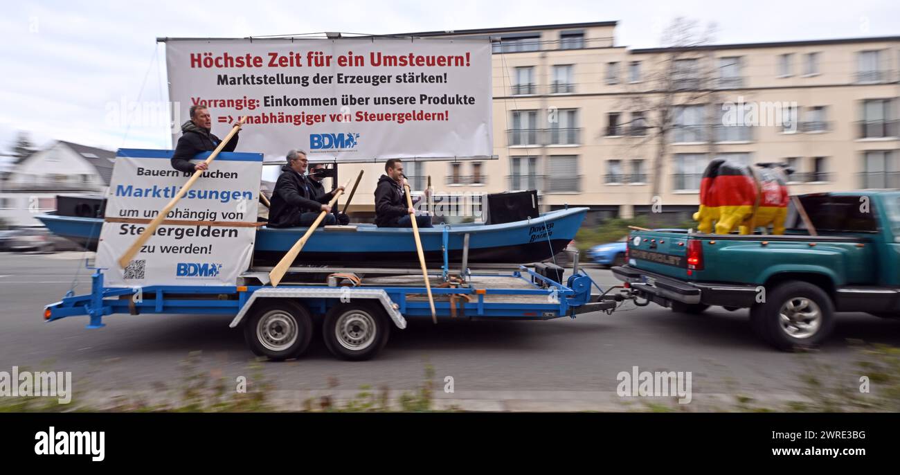 Erfurt, Germania. 12 marzo 2024. I dimostranti guidano con una barca su un rimorchio fino agli uffici statali di CDU, FDP, Linke, Greens e SPD. La protesta dell'Associazione federale dei produttori lattiero-caseari tedeschi si svolge con lo slogan "Turn the mares, change the Course of Agricultural market policy!”. E si svolge poco prima della Conferenza dei Ministri dell'Agricoltura (AMK). I rappresentanti federali e statali si incontreranno all'AMK di Erfurt dal 13 al 15 marzo. Crediti: Martin Schutt/dpa/Alamy Live News Foto Stock