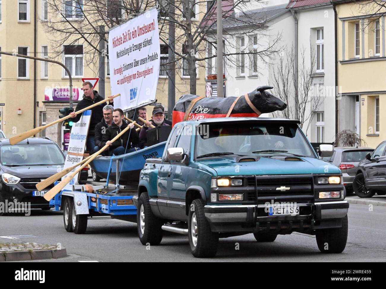 Erfurt, Germania. 12 marzo 2024. I dimostranti guidano con una barca su un rimorchio fino agli uffici statali di CDU, FDP, Linke, Greens e SPD. La protesta dell'Associazione federale dei produttori lattiero-caseari tedeschi si svolge con lo slogan "Turn the mares, change the Course of Agricultural market policy!”. E si svolge poco prima della Conferenza dei Ministri dell'Agricoltura (AMK). I rappresentanti federali e statali si incontreranno all'AMK di Erfurt dal 13 al 15 marzo. Crediti: Martin Schutt/dpa/Alamy Live News Foto Stock