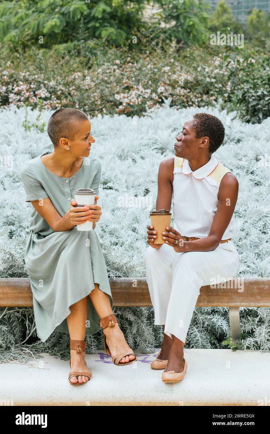 Due donne d'affari stanno bevendo un caffè nel parco. Foto Stock