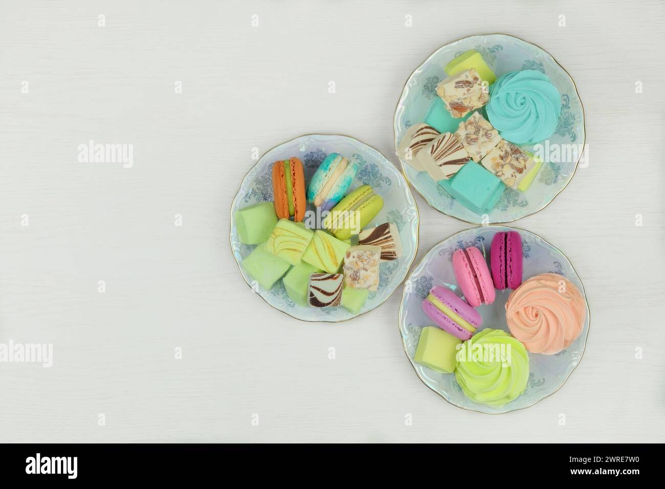 Vari dessert. Dolci dessert in piatti per le vacanze. Macaron, marshmallow e zephyrs su sfondo bianco. Vista dall'alto. Foto Stock