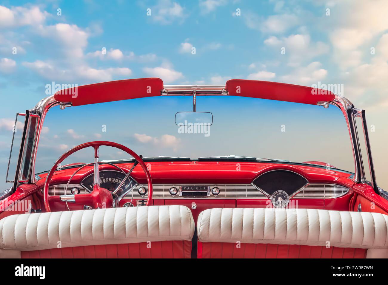 Vista del conducente di una classica cabriolet rossa d'epoca americana aperta di fronte a un cielo azzurro e soleggiato Foto Stock