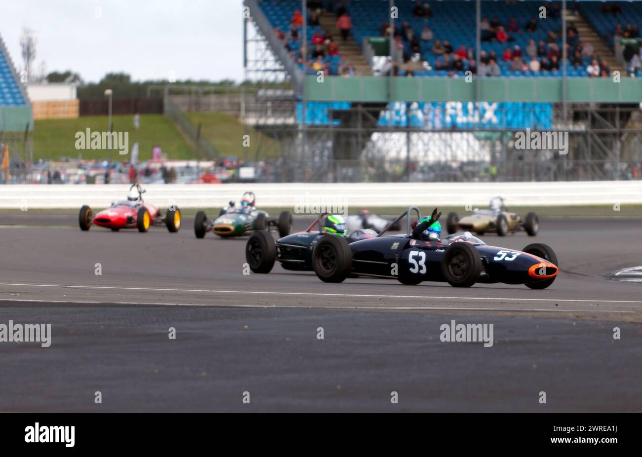 Sam Wilson, sventolando dal pozzetto della sua Green, 1963, Cooper T59, dopo aver vinto la Historic Formula Junior Race al Silverstone Festival 2023 Foto Stock