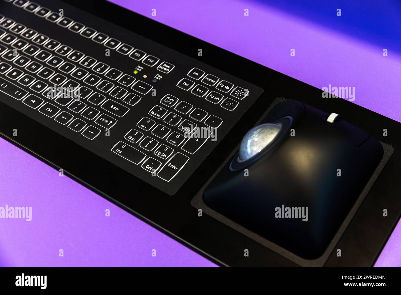 Dispositivo di inserimento dati industriale da tavolo integrato con tastiera nera e mouse con trackball. Moderne apparecchiature elettroniche di navigazione montate presso il Captains brid Foto Stock