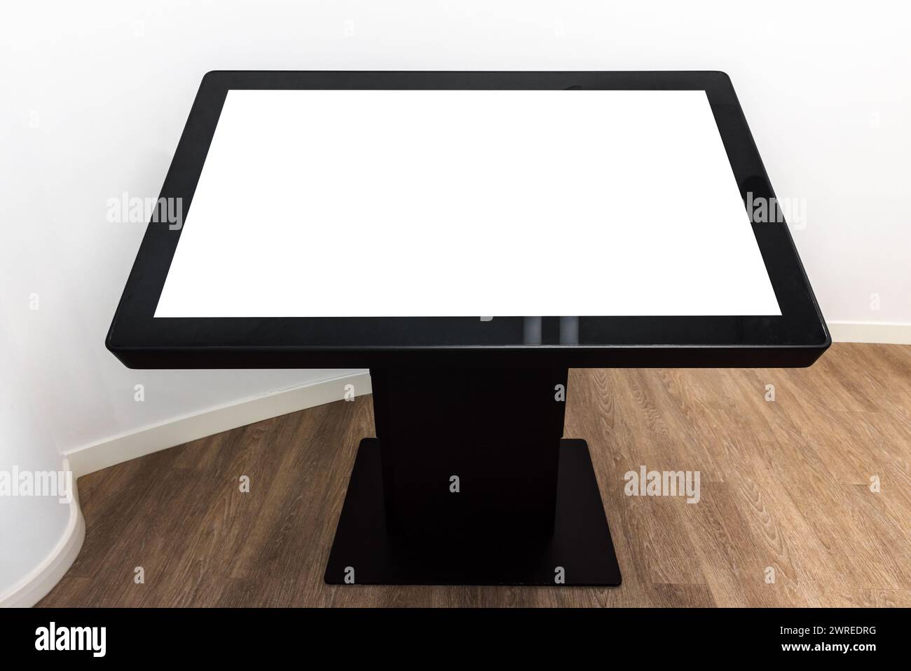 Tavolino interattivo nero con schermo vuoto, interno bianco su pavimento in legno, mockup high-tech Foto Stock