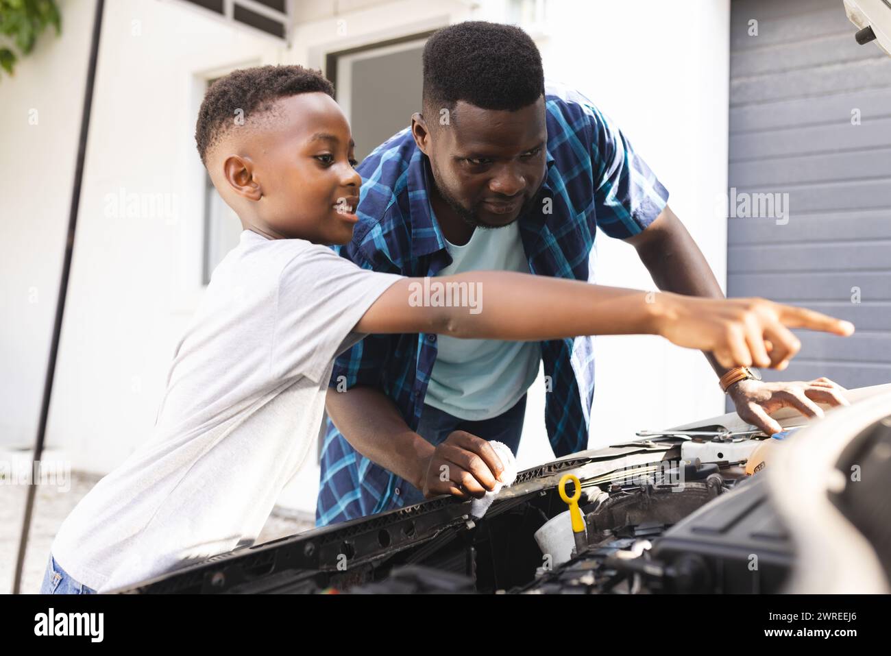 Padre e figlio afroamericani lavorano insieme su un motore per auto Foto Stock