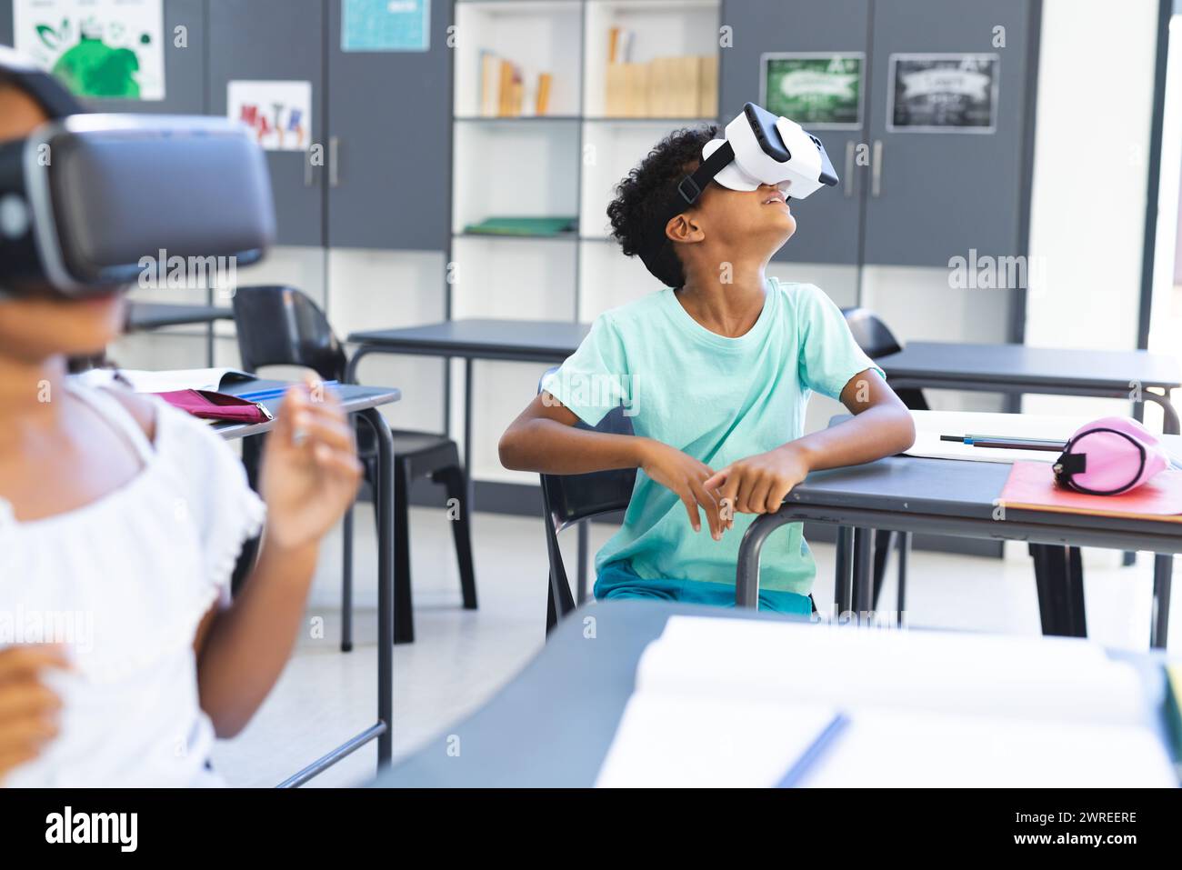 I bambini birazziali esplorano con i visori VR in una classe a scuola Foto Stock