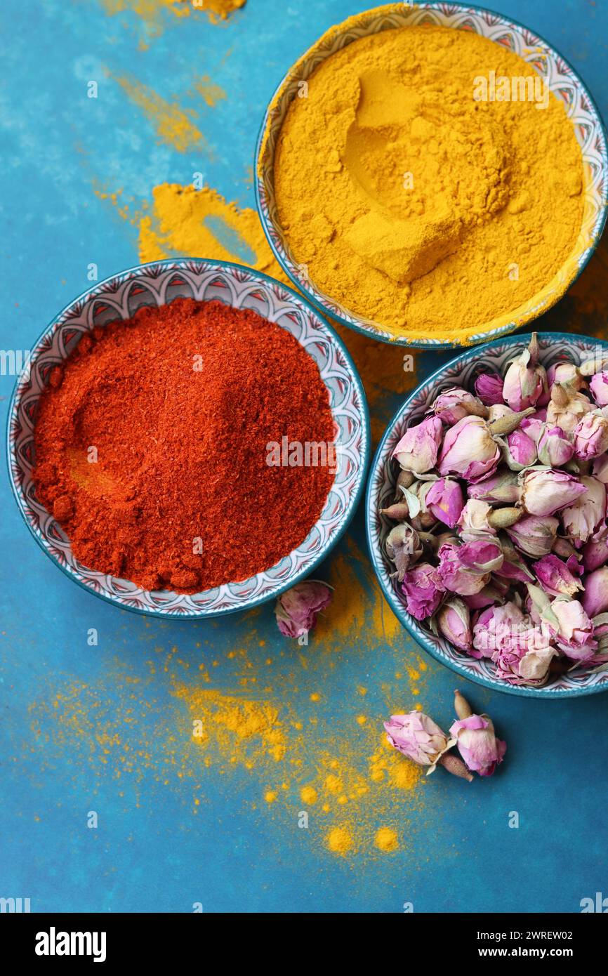 Foto ravvicinata di gemme di rose secche. Fiori di rosa in una ciotola di ceramica blu. Ingrediente del tè alle erbe. Sfondo blu con spazio di copia. Foto Stock