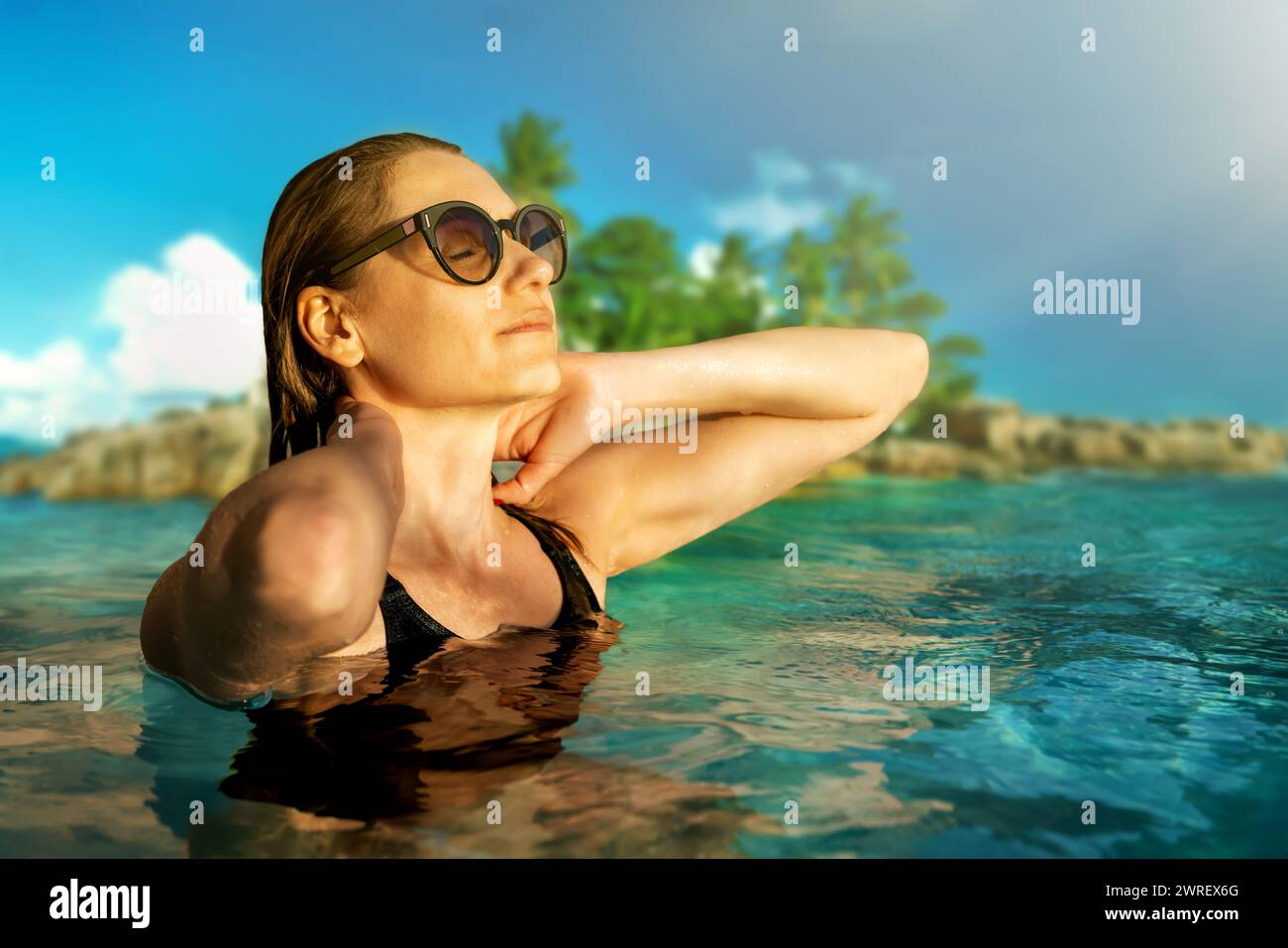 Donna con occhiali da sole che gode di vacanze e sole sul viso nell'oceano alle isole tropicali delle Seychelles Foto Stock