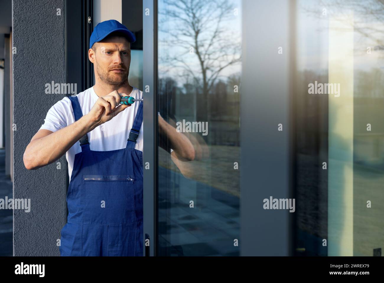 operatore che installa e regola le porte scorrevoli della terrazza con telaio in alluminio Foto Stock
