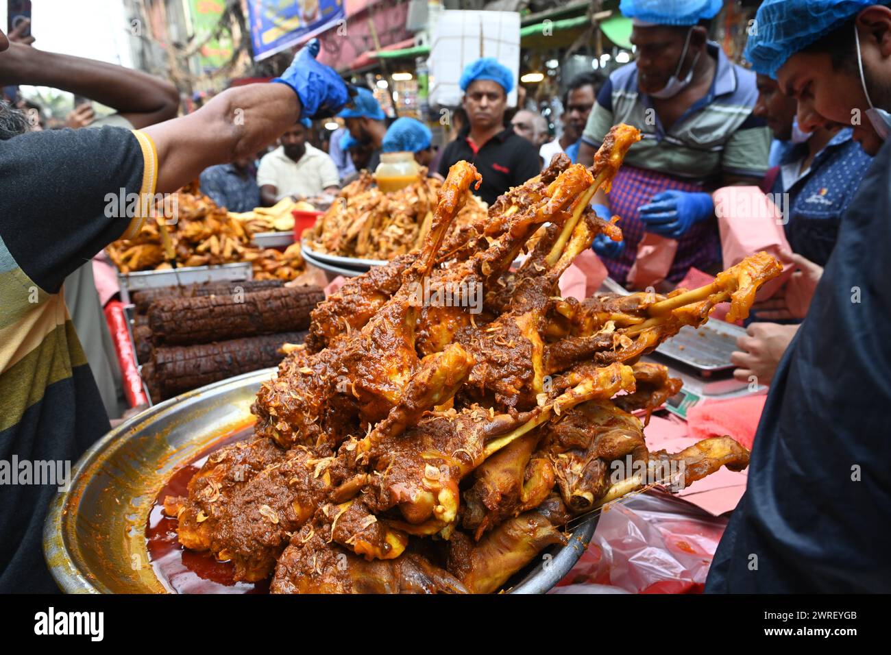 Il venditore di strada vende alimenti iftar per rompere il digiuno diurno del mese sacro del Ramadan in un tradizionale mercato iftar a Dacca, Bangladesh, il 12 marzo 2024 Foto Stock