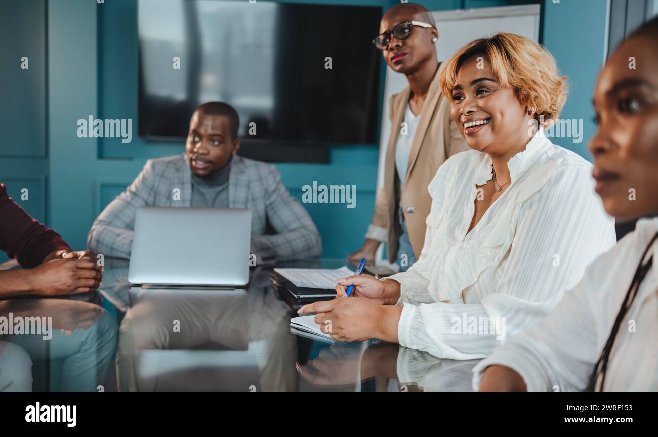 Gruppo di colleghi di sesso maschile e femminile in un ufficio aziendale, impegnato in una riunione aziendale di successo. Mostrano lavoro di squadra, felicità e professionalità Foto Stock