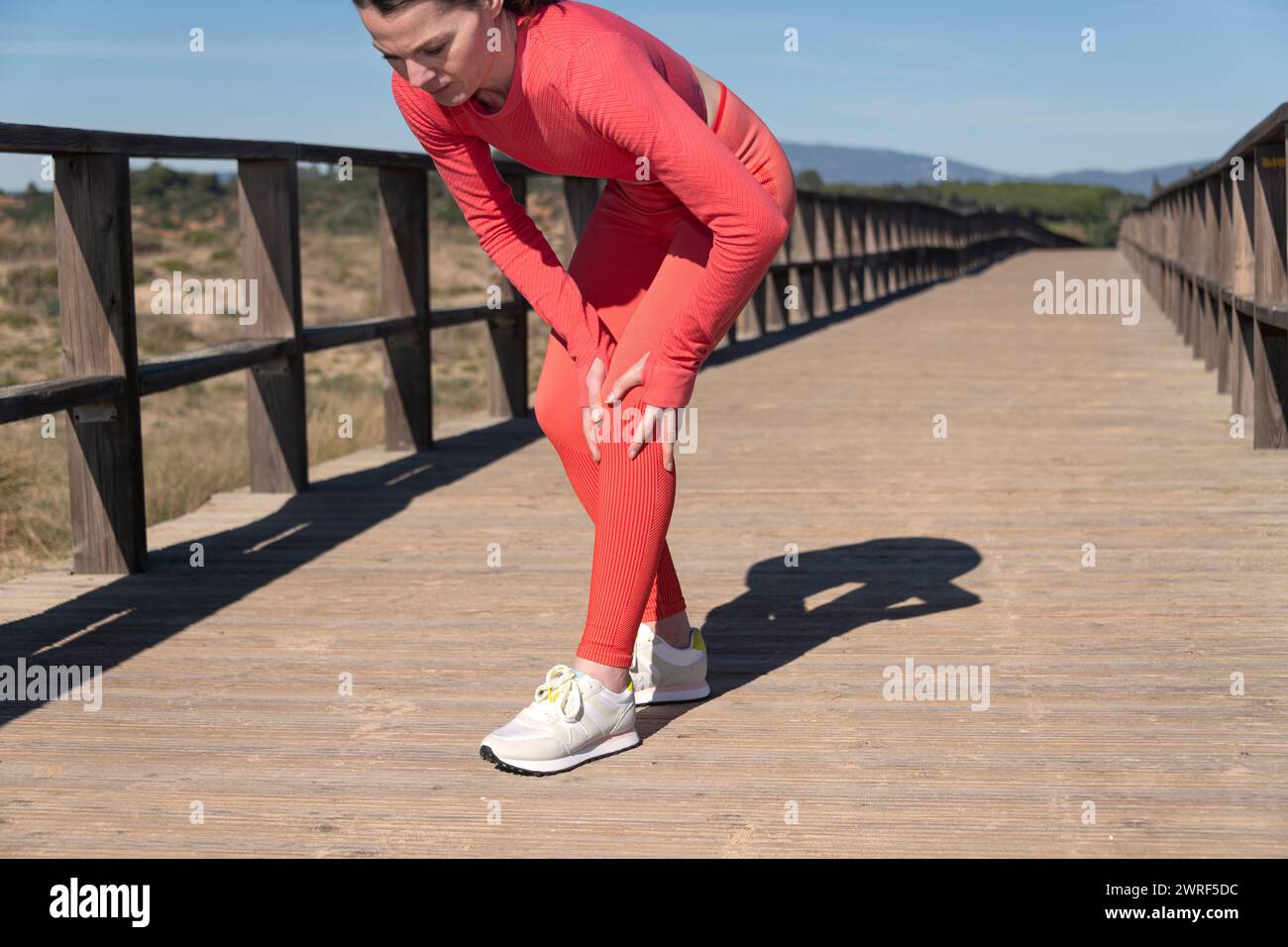 Primo piano di una atleta sportiva che tiene il ginocchio, concetto di infortunio sportivo. Foto Stock