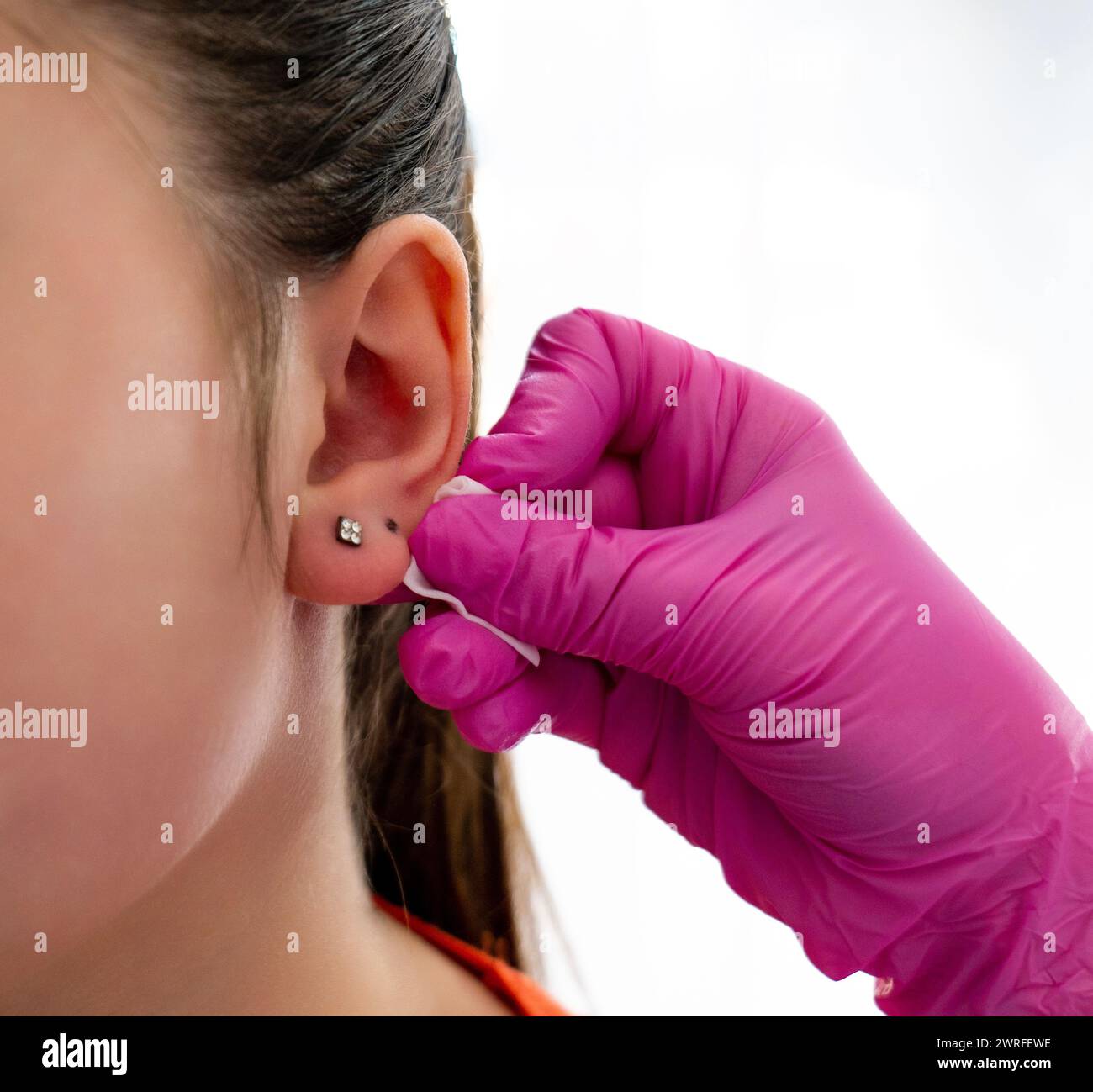 L'orecchio del cliente segnato dal medico professionista attraverso un punto con l'aiuto della penna speciale per perforare in un salone di bellezza. Foto di alta qualità Foto Stock