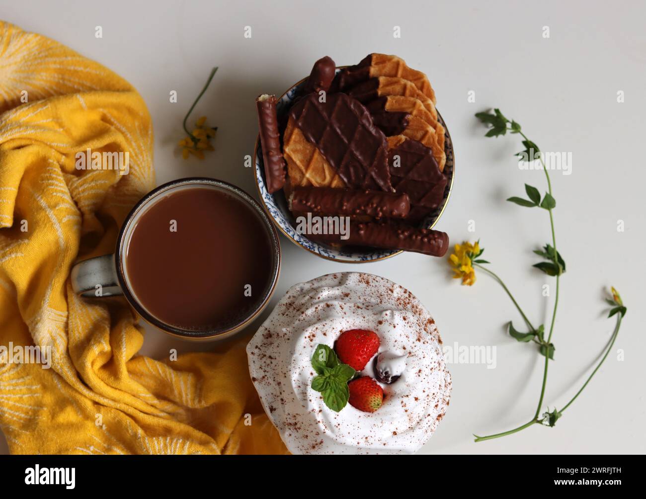 Vista dall'alto della tazza di tè al latte, waffle e biscotti in una ciotola. Foto da vicino del cibo dolce. Sfondo bianco con spazio per il testo. Foto Stock