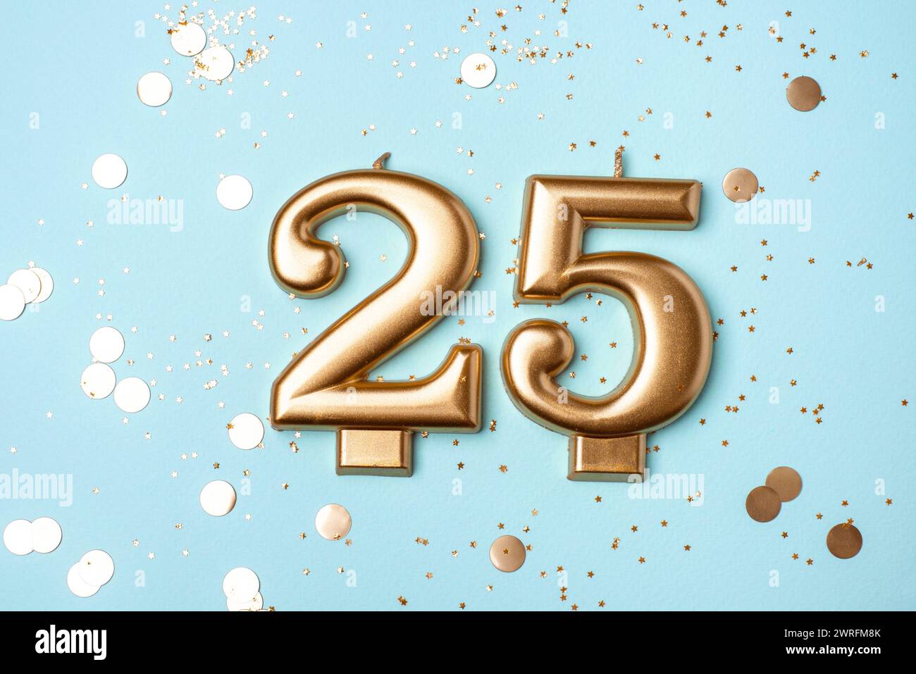 Candele d'oro in forma di numero venticinque su sfondo blu con coriandoli. festeggiamenti per i 25 anni. Foto Stock