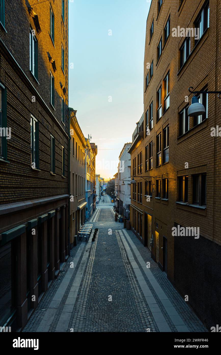 Strada vuota all'alba con torreggianti pareti in mattoni su ogni lato. Nessuna persona visibile Foto Stock