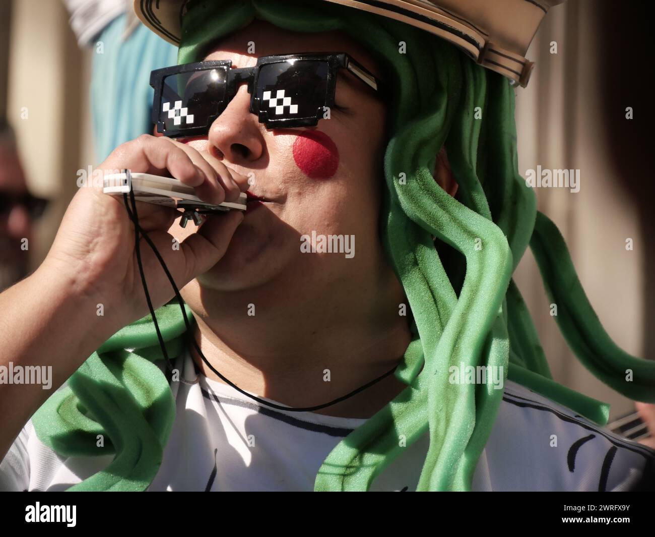 I goer di Carnevale soffiano un fischio durante il festival, a Cadice, Spagna, febbraio 2024 Foto Stock