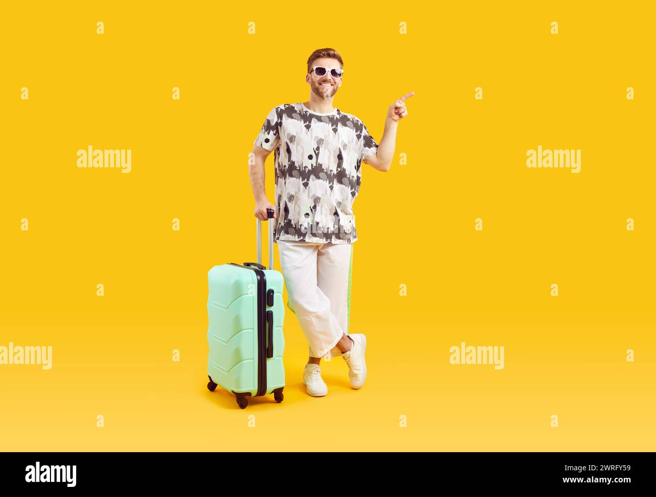 Un giovane con occhiali da sole e valigia va in vacanza estiva su sfondo giallo. Foto Stock