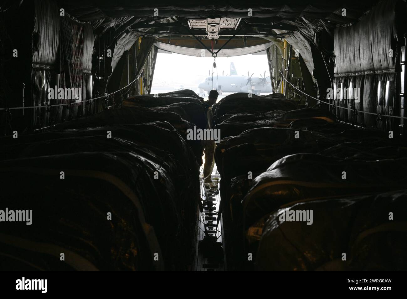 Un comandante dell'aeronautica statunitense ispeziona pallet di rifornimenti di acqua e cibo confezionati per gli aiuti umanitari in diverse località Foto Stock