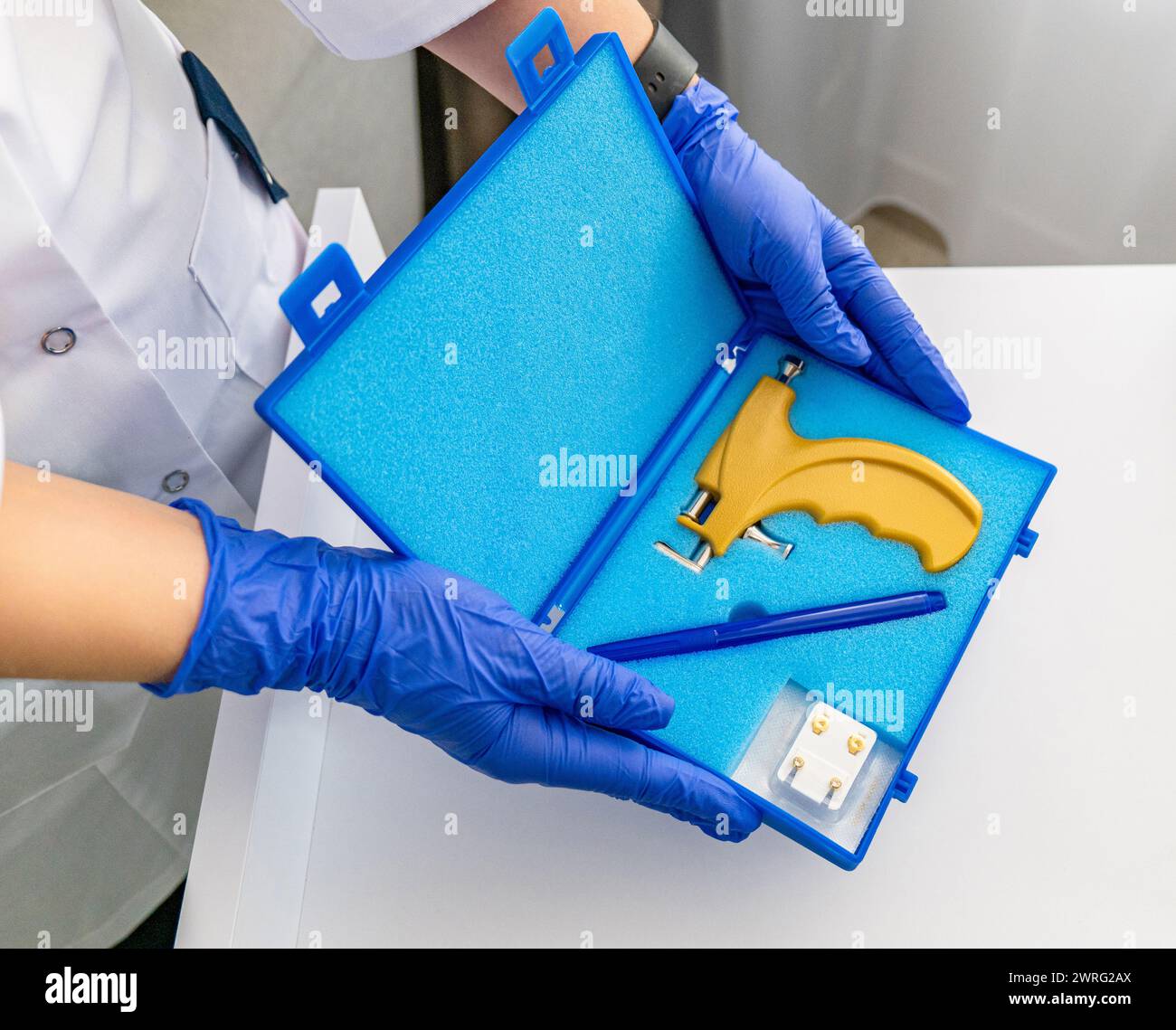 Utensili professionali per perforare l'orecchio in una speciale scatola blu della pistola perforatrice. Foto di alta qualità Foto Stock
