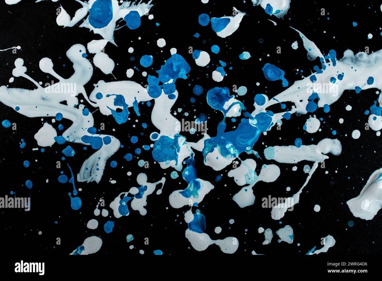 Spruzzi di vernice bianca e blu sparsi su sfondo nero Foto Stock