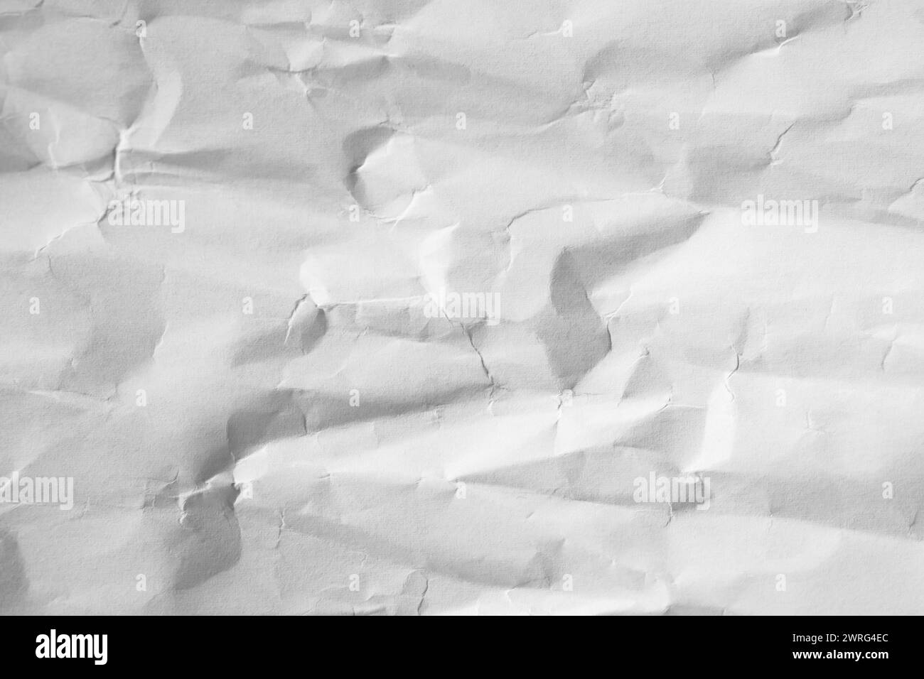Carta bianca arricciata da rughe ombreggiate, primo piano con messa a fuoco morbida, texture astratta Foto Stock