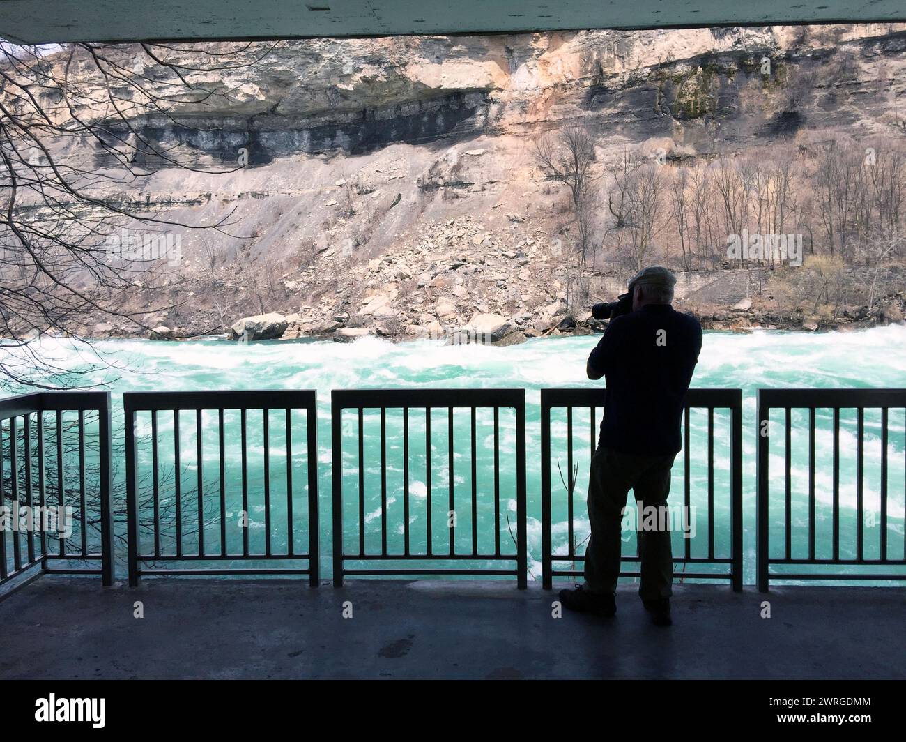 Un fotografo che scatta foto lungo il fiume Niagara, appena sotto le cascate del Niagara, sulla White Water Walk, una famosa attrazione dei parchi del Niagara. Foto Stock
