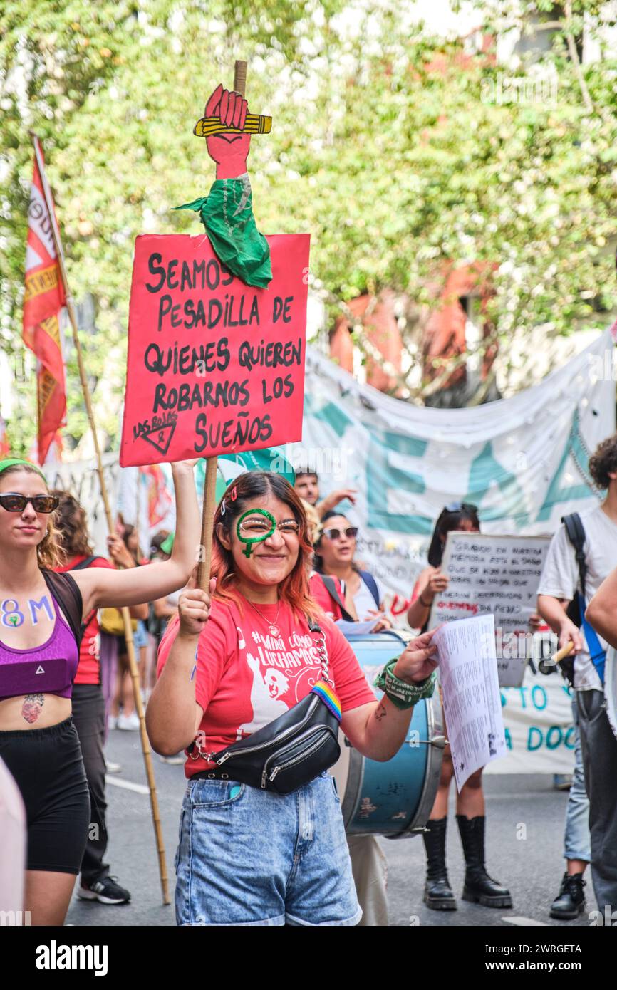 Buenos Aires, Argentina; 8 marzo 2024: 8M sciopero femminista. La giovane donna sorride guardando la telecamera mentre marcia con un cartello: Facciamo noi il ni Foto Stock