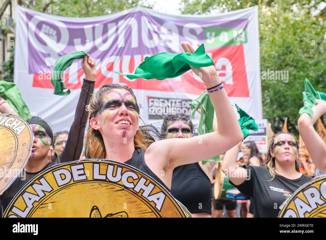 Buenos Aires, Argentina; 8 marzo 2024: Giovane donna che canta slogan femministi sventolando una sciarpa verde e tenendo uno scudo con il testo piano di lotta, durin Foto Stock